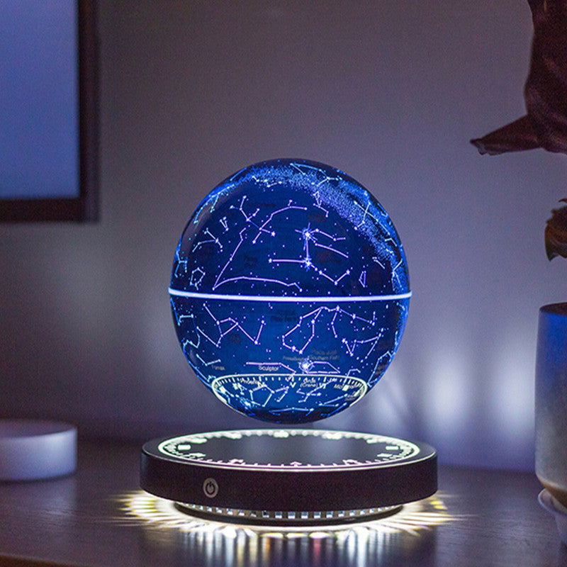Levitating star globe lamp: deep-blue constellation globe floating above a black base with a lit rim, on a dark desk